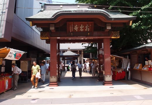 Red gate entrance to Koganji Temple in Sugamo Tokyo with shoppers