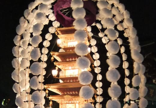 Illuminated multi-tiered mando lantern tower with white paper flowers at Ikegami Honmonji Oeshiki festival
