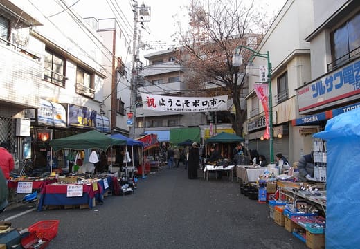Narrow street lined with market stalls and banners at Setagaya Boroichi flea market