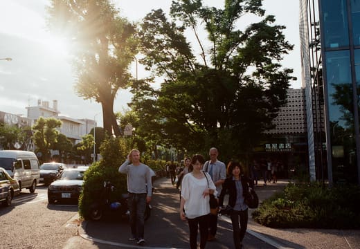 Pedestrians on a tree-lined Daikanyama street in low afternoon sun