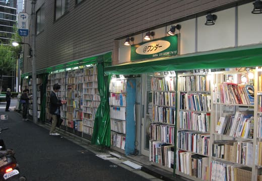 Second-hand bookshop shelves along a covered walkway in Kanda-Jimbocho in the evening