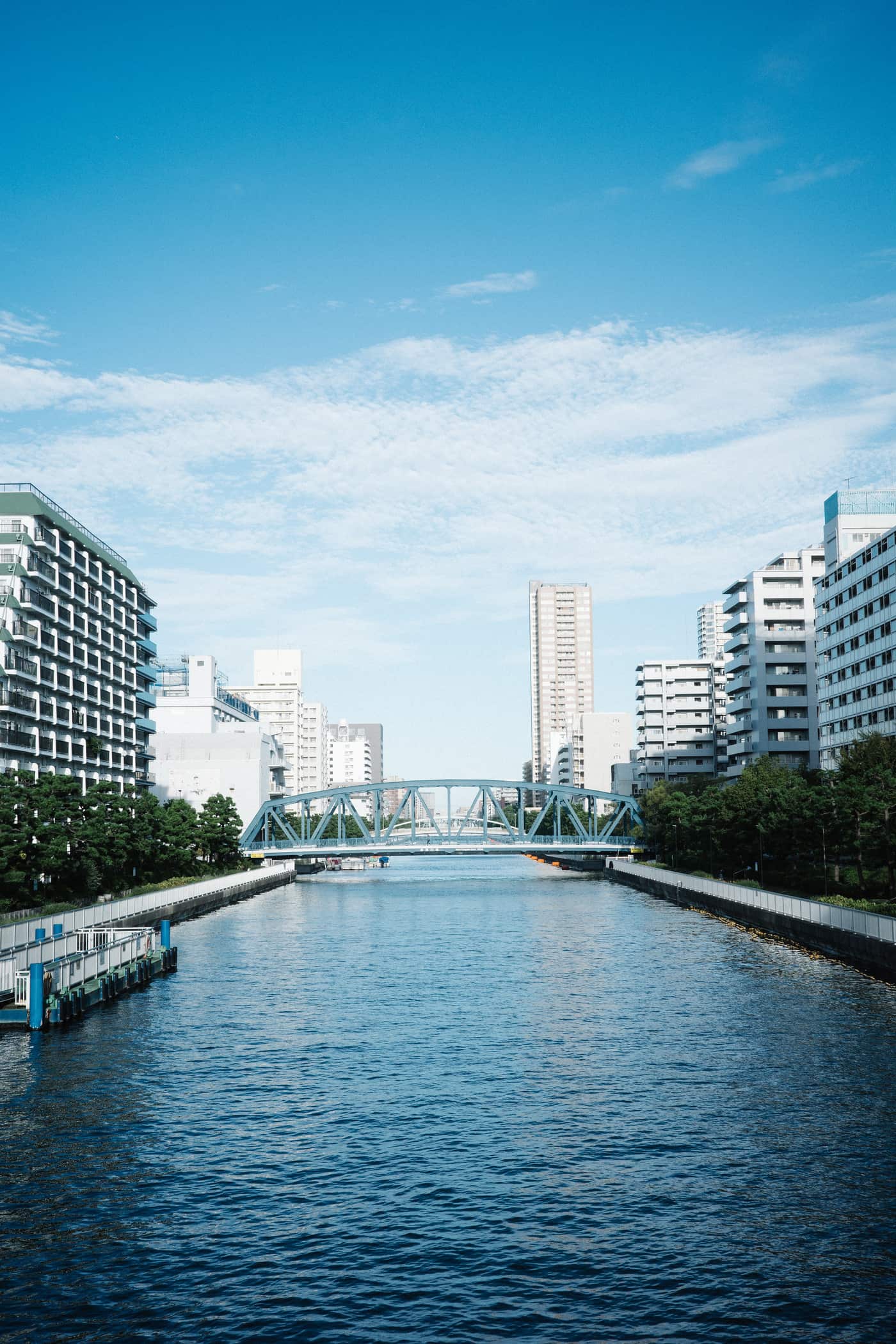 Tree-lined canal and waterfront apartment blocks in Kiyosumi-Shirakawa on a sunny day