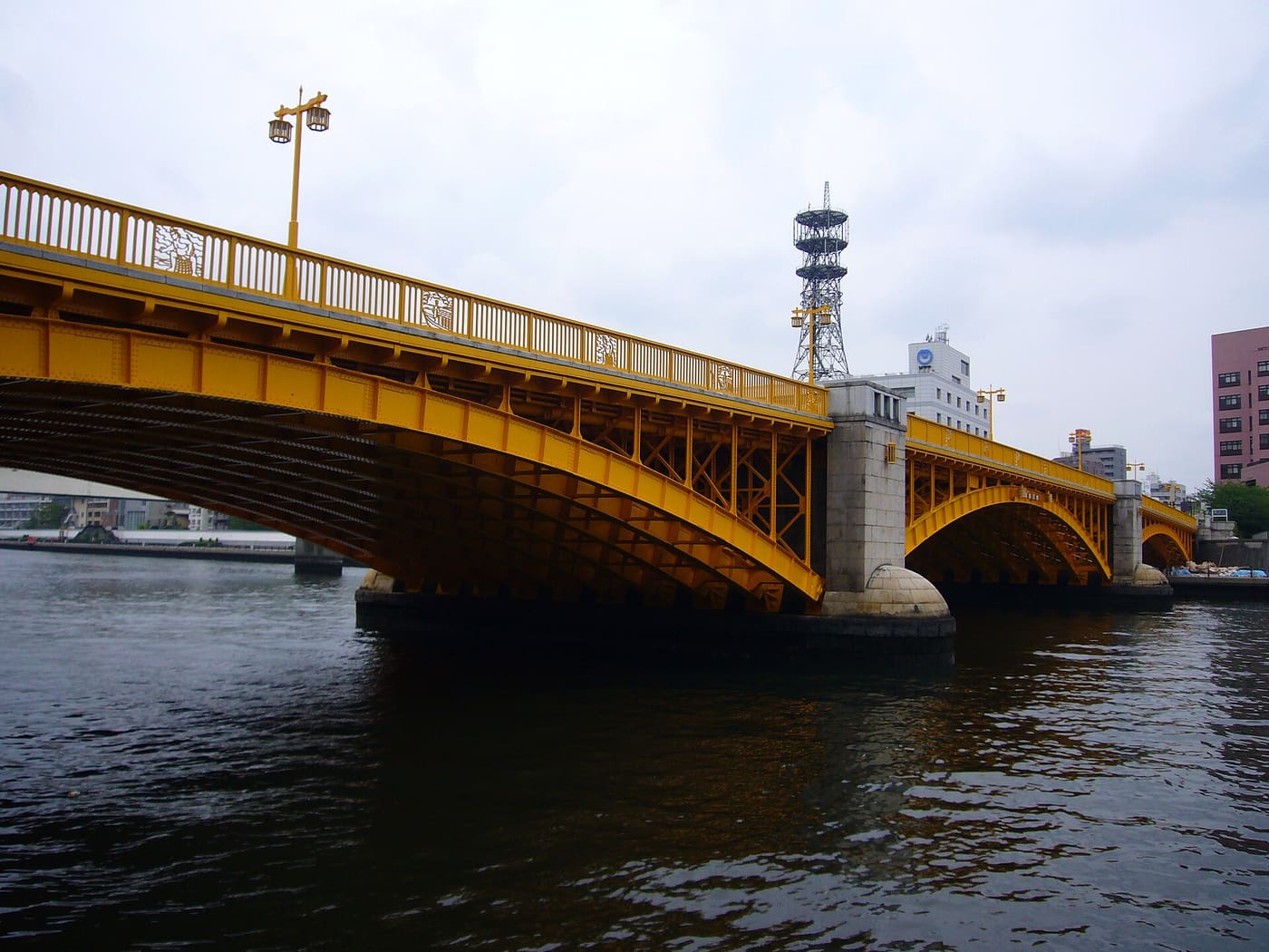 The yellow steel arches of Kuramae Bridge spanning the Sumida River