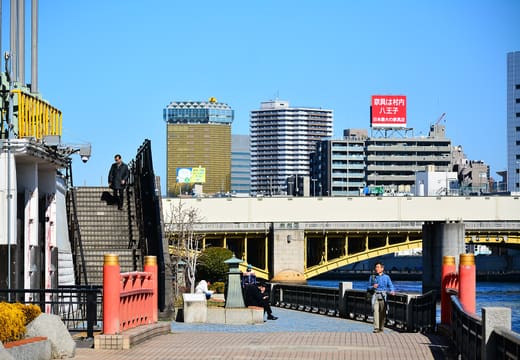 Sumida riverside terrace walkway in Kuramae with the yellow Kuramae Bridge beyond