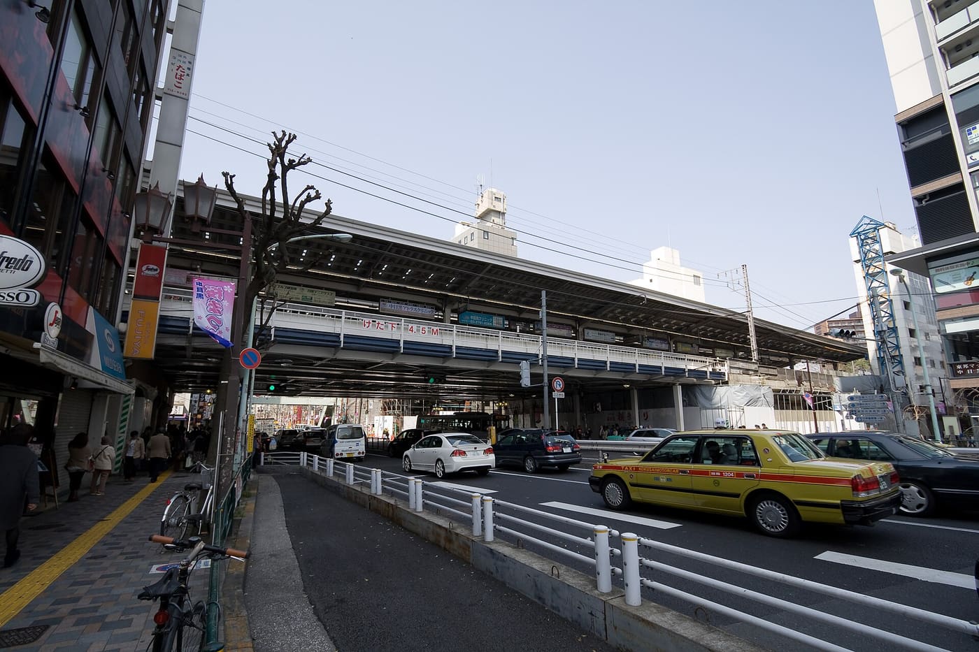 Nakameguro Station beneath the elevated Tokyu Toyoko Line tracks with a taxi passing