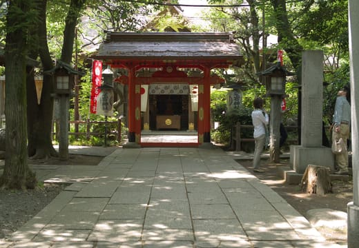 Vermilion gate and stone-paved approach under trees at Atago Shrine, Toranomon