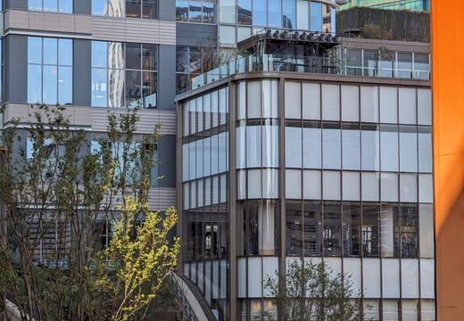 Glass-fronted buildings and spring greenery in the landscaped plaza of Azabudai Hills