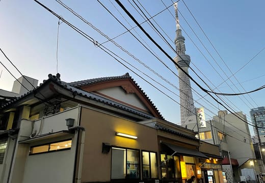 Oshiage Onsen Daikokuyu's temple-style roof with Tokyo Skytree rising behind it