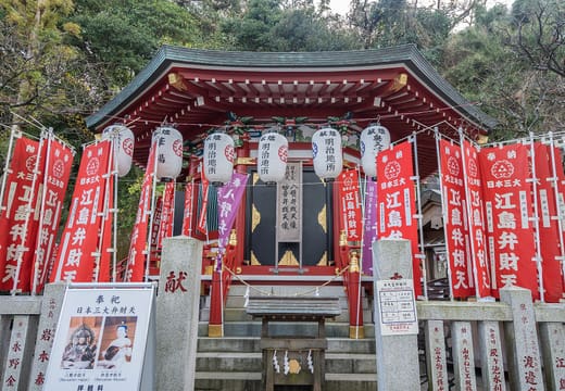 Red Benzaiten banners and lanterns in front of a vermilion hall at Enoshima Shrine