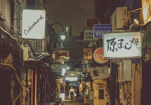 Quiet lamplit lane of Golden Gai at midnight with bar signs glowing, Shinjuku