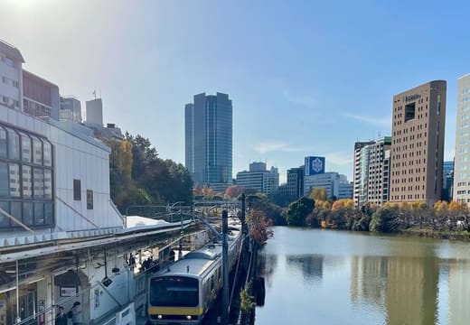 Yellow Sobu Line train running beside the calm Ichigaya outer moat