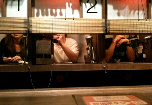 Row of solo ramen booths with bamboo blinds at the Ichiran counter in Shibuya