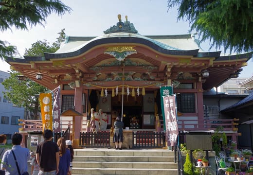 Visitors at the pink and green worship hall of Imado Shrine, birthplace of the maneki-neko