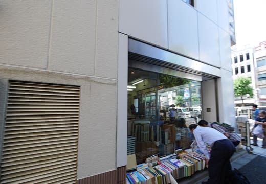 Shoppers browsing bargain book carts along the side wall of Isseido Booksellers, Jimbocho