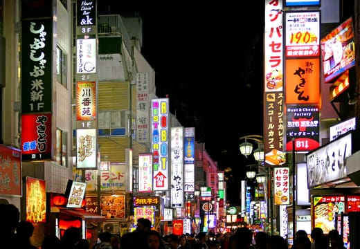 Stacked neon signs of bars and restaurants lining a Kabukicho street at night