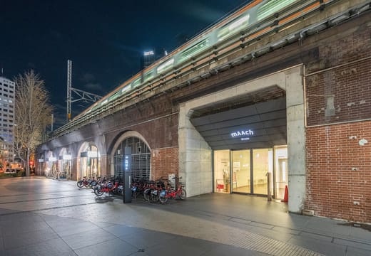 Lit brick arches of the mAAch ecute viaduct along the Kanda River at night