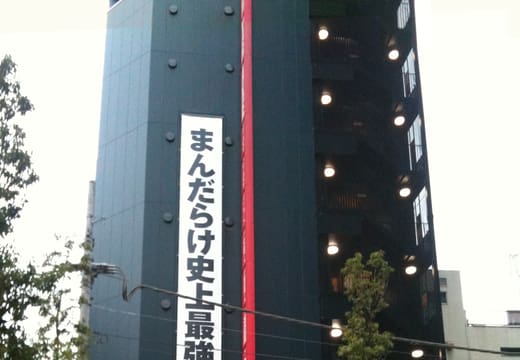 Tall black Mandarake Complex tower with its vertical sign on a side street in Akihabara