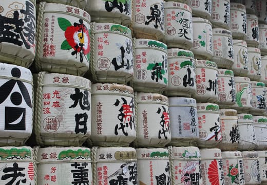 Wall of decorated sake barrels offered to Meiji Shrine along the forest path in Harajuku