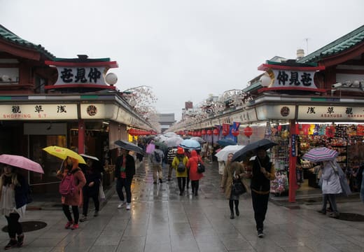 Shoppers with umbrellas walking Nakamise shopping street on a rainy day in Asakusa