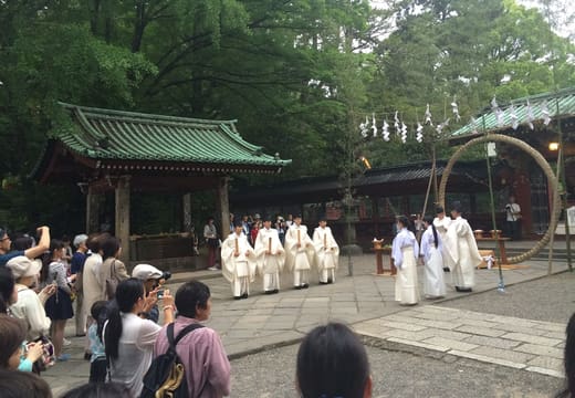 Priests in white robes beside the chinowa grass ring during summer purification at Nezu Shrine