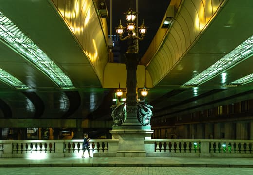 Ornate lamp posts glowing on Nihonbashi Bridge beneath the expressway at night