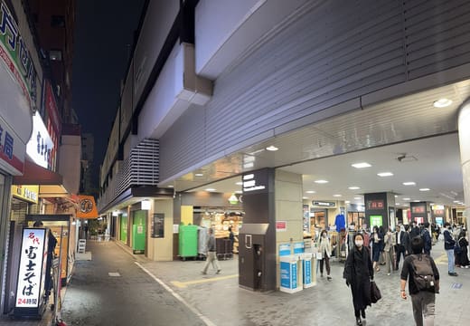 Shops lining the walkway beneath the elevated tracks at Sasazuka Station at night