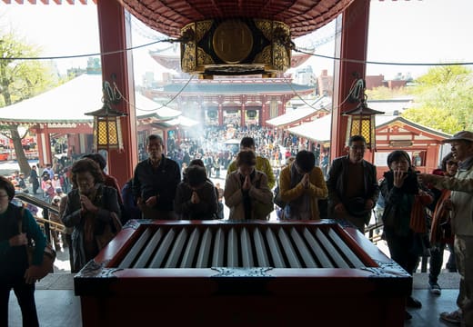 Worshippers praying at the offering box beneath the great lantern of the Senso-ji main hall