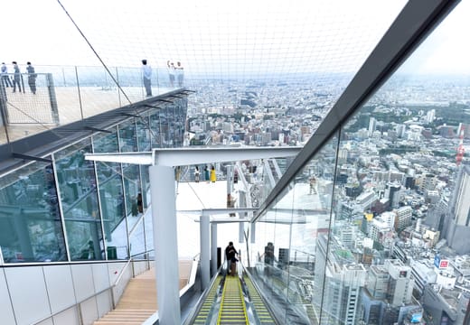 Glass-walled escalator rising to the rooftop of Shibuya Sky high above the city
