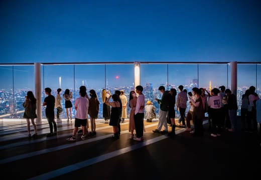 Visitors lining the glass edge of the Shibuya Sky rooftop deck at blue hour