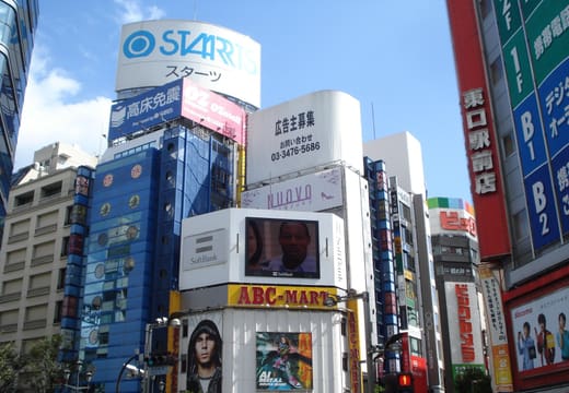 Crowded shopping streets and big signs around the east exit of Shinjuku Station