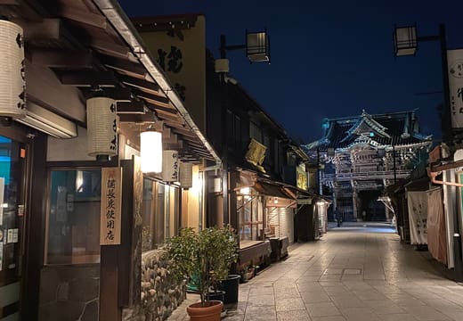 Taishakuten Sando at dusk with shop lanterns and the temple gate glowing at the far end