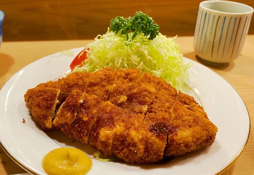 Golden tonkatsu with shredded cabbage and mustard on the counter at Tonki, Meguro