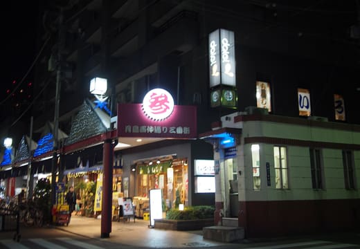 Lit Tsukishima Monja Street sign and restaurants along the street at night