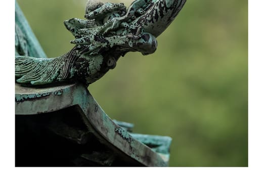 Curled dragon finial on a weathered copper lantern at Ueno Toshogu Shrine