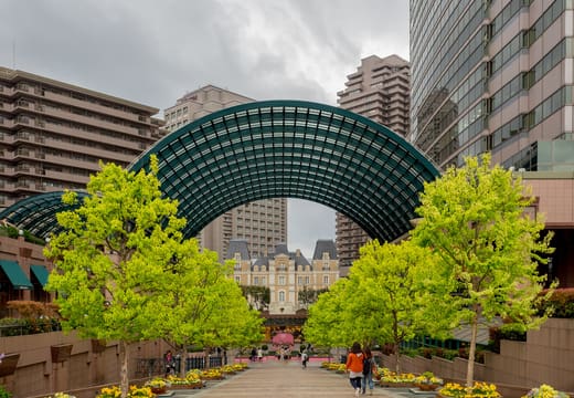 Glass-roofed arcade and plaza of Yebisu Garden Place framed by fresh spring trees