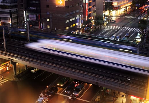 Shinkansen streaking along the elevated tracks above Yurakucho streets at night