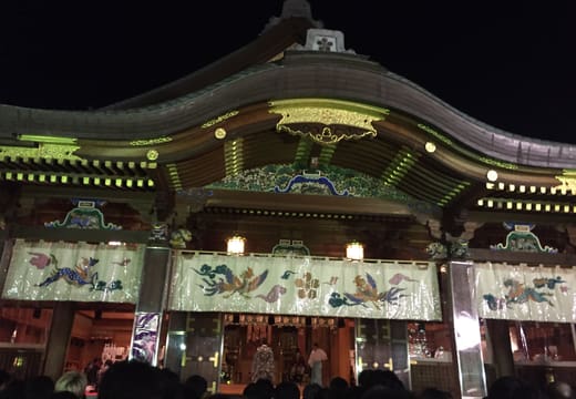 Yushima Tenman-gu worship hall lit up at night with its carved gables and lanterns