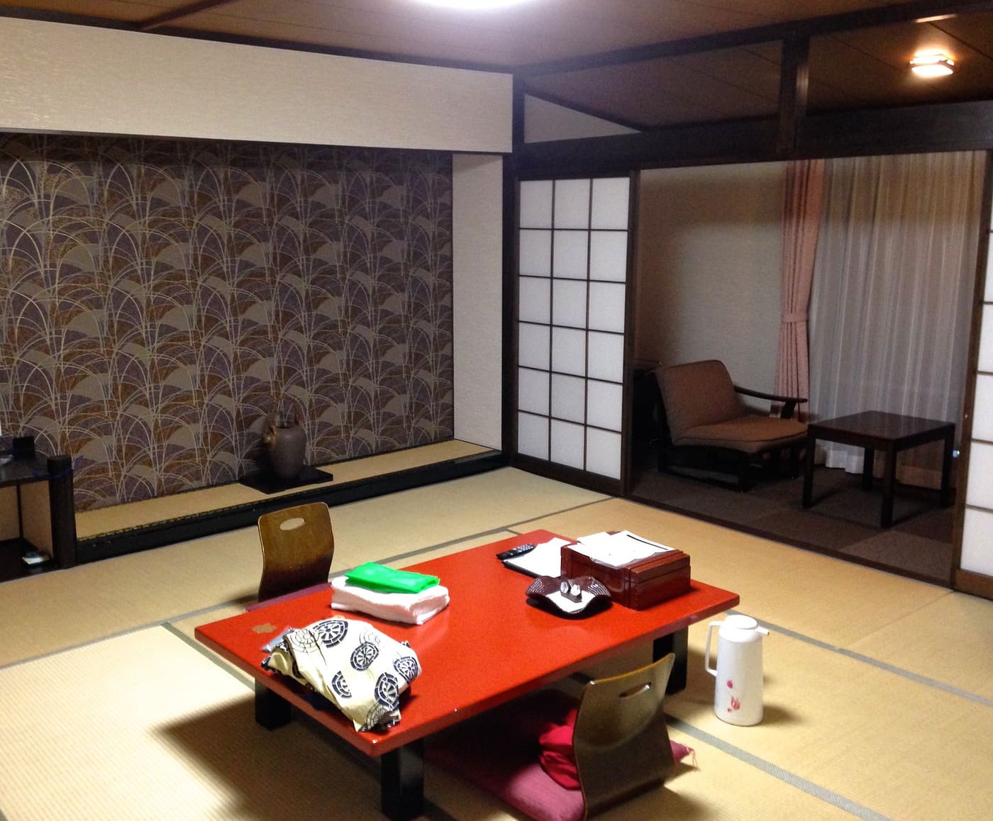 Une chambre de ryokan à Hakone, avec tatamis, table basse rouge et cloisons shoji