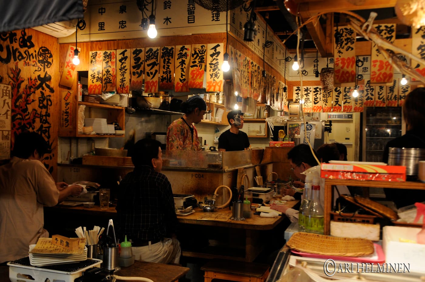Diners at wooden tables in a lantern-lit izakaya in Kabukicho, Shinjuku