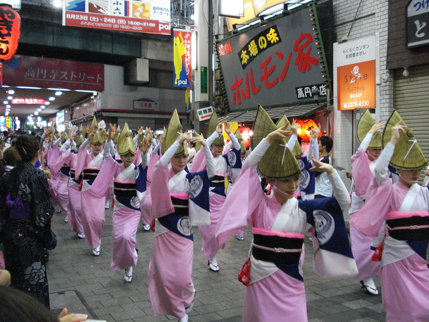 Women dancers in straw amigasa hats moving down a Koenji shopping street