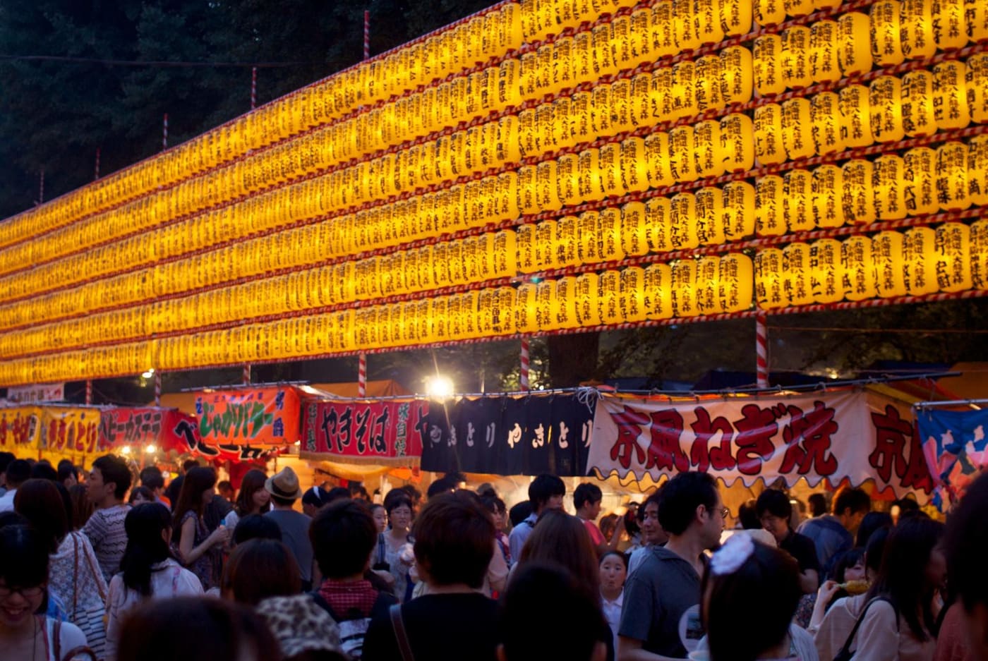 Rows of lit lanterns above food stalls and crowds at the Mitama Matsuri, Yasukuni Shrine