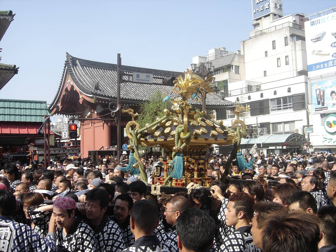 Bearers in matching happi coats shouldering a mikoshi through an Asakusa street