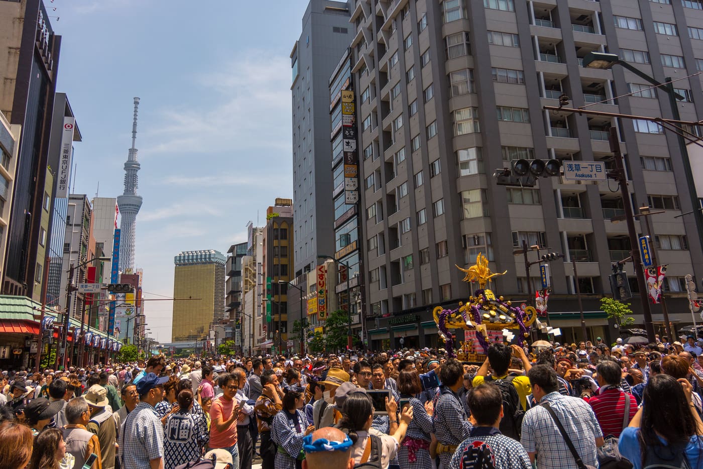 Neighbourhood mikoshi and bearers filling an Asakusa street with Tokyo Skytree behind