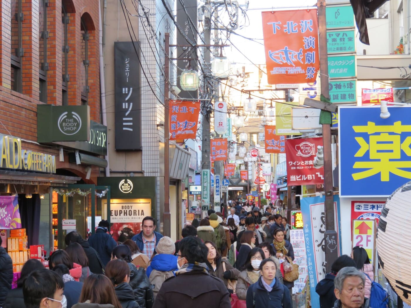 下北沢の看板が並ぶ細い商店街を歩く買い物客