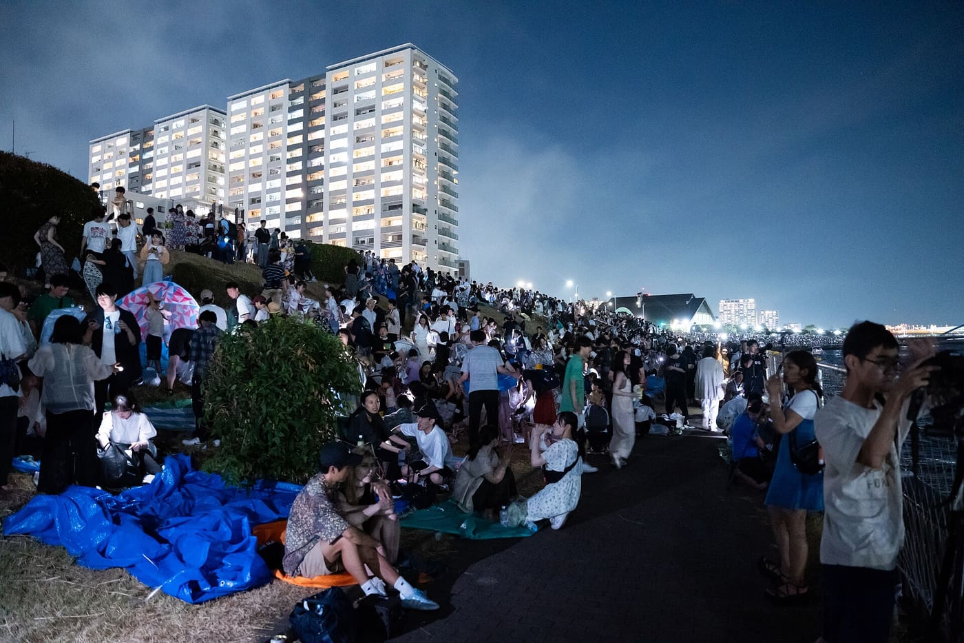 Spectators on picnic sheets along the Sumida River embankment waiting for the fireworks