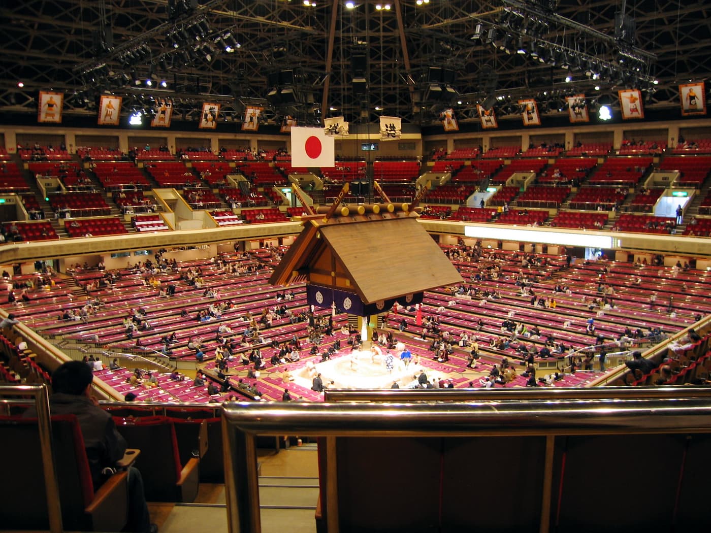 The dohyo under its suspended shrine roof inside Ryogoku Kokugikan on a tournament day