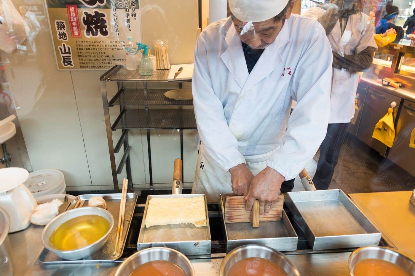 A cook slicing tamagoyaki omelette at a stall in Tsukiji Outer Market