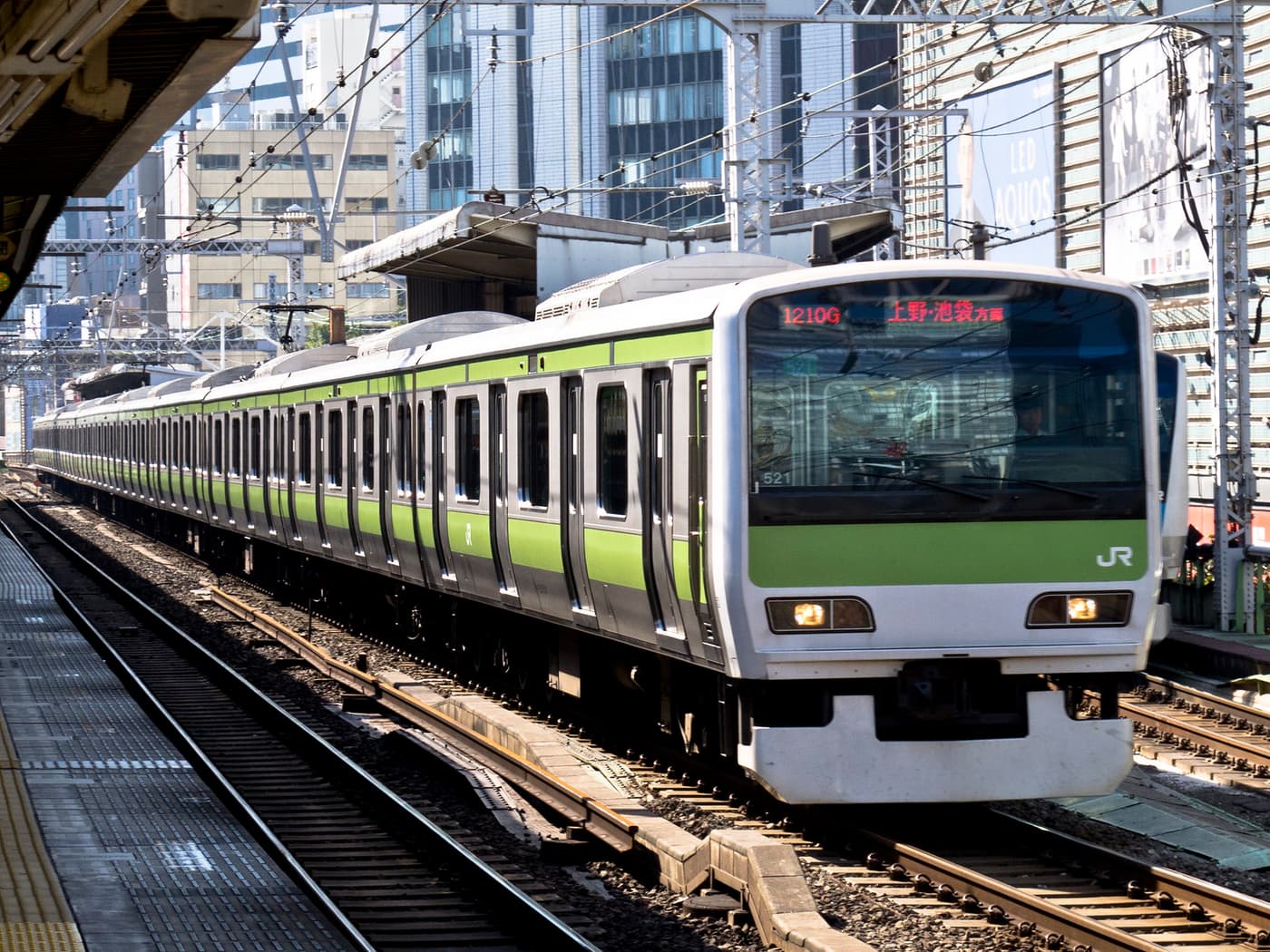A green-striped Yamanote Line train at a station platform in Tokyo
