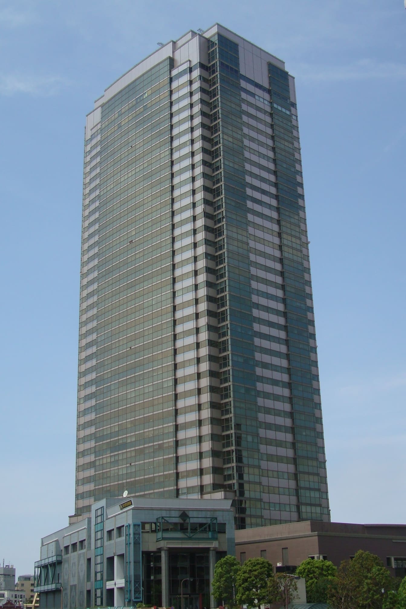 Yebisu Garden Place Tower rising over Ebisu against a clear blue sky