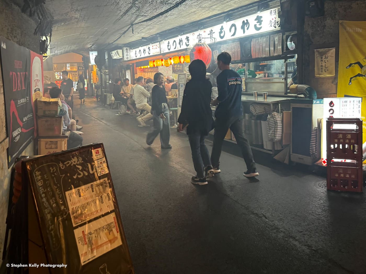 Yakitori smoke drifting through an izakaya corridor under the railway arches at Yurakucho